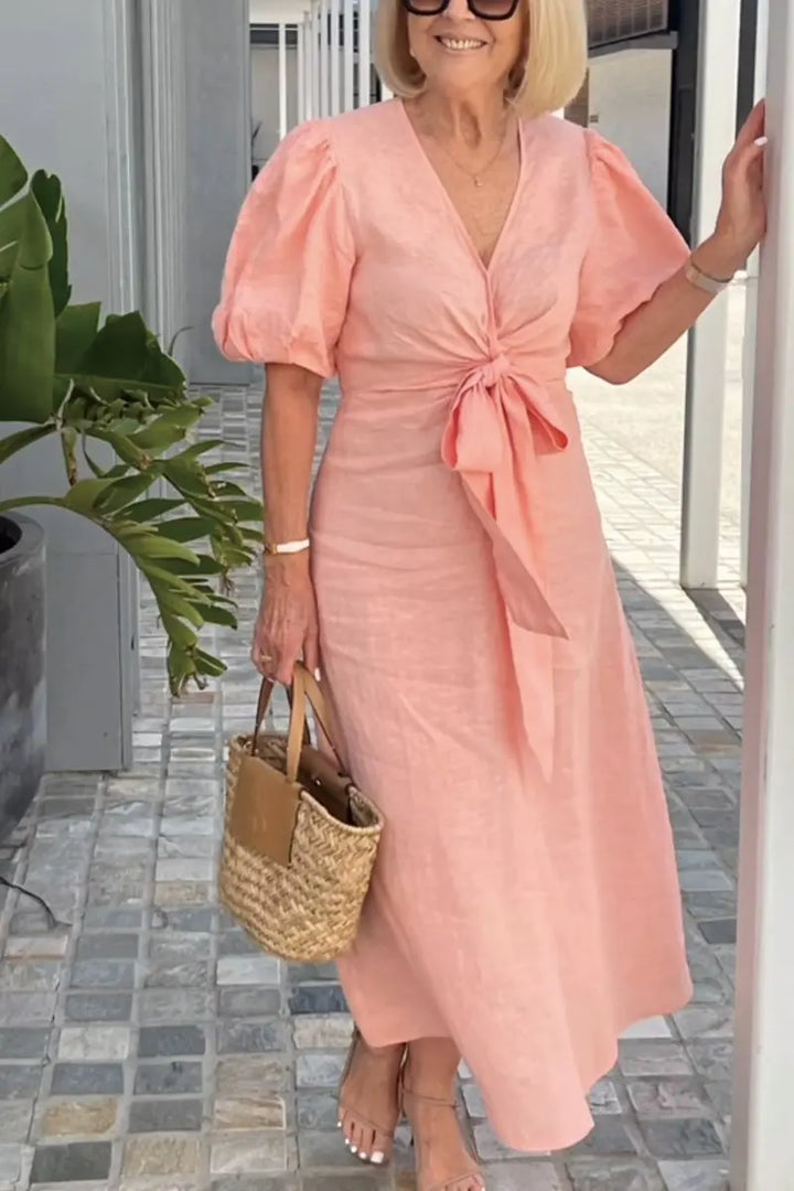 Woman wearing the Bridget bow-front midi dress with puff sleeves at a garden party.