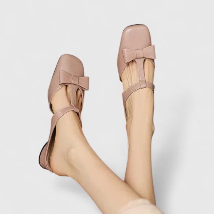 A woman wearing soft pink comfort sandals with a broad, cushioned footbed on a sunny day.
