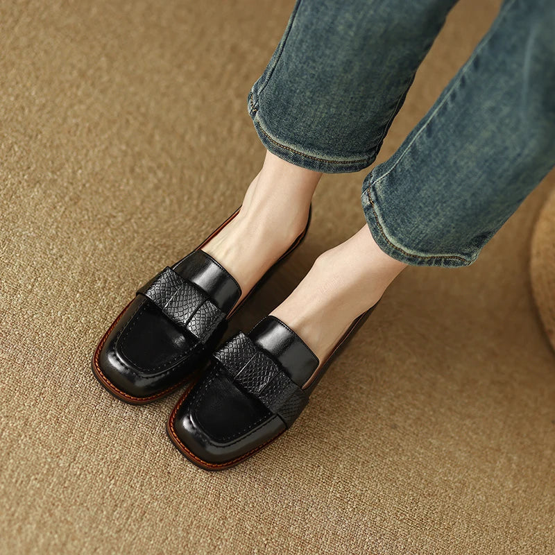 A woman wearing classic loafers with a subtle knot detail and tailored trousers