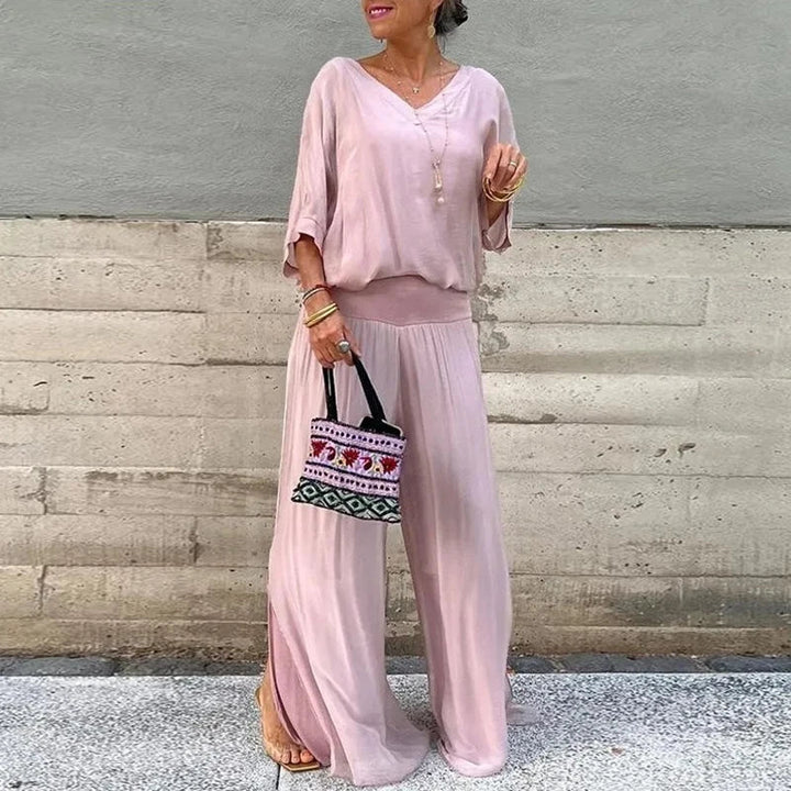 A woman wearing a flowing lounge two-piece set with a V-neck top and wide-leg trousers.