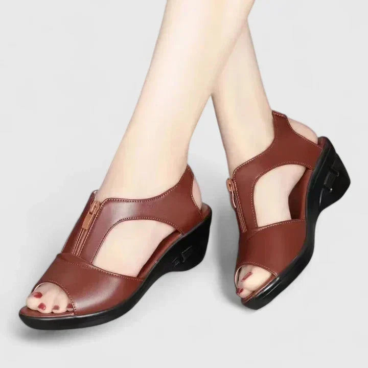 A woman wearing wine red elegant sandals with a broad, cushioned footbed.