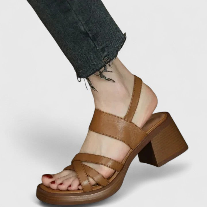 A woman wearing elegant cross-strap sandals with a summer dress, looking graceful and comfortable.