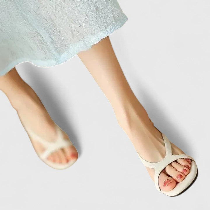 Cream toe-post sandals with a slingback buckle and a block heel set with a pearl.