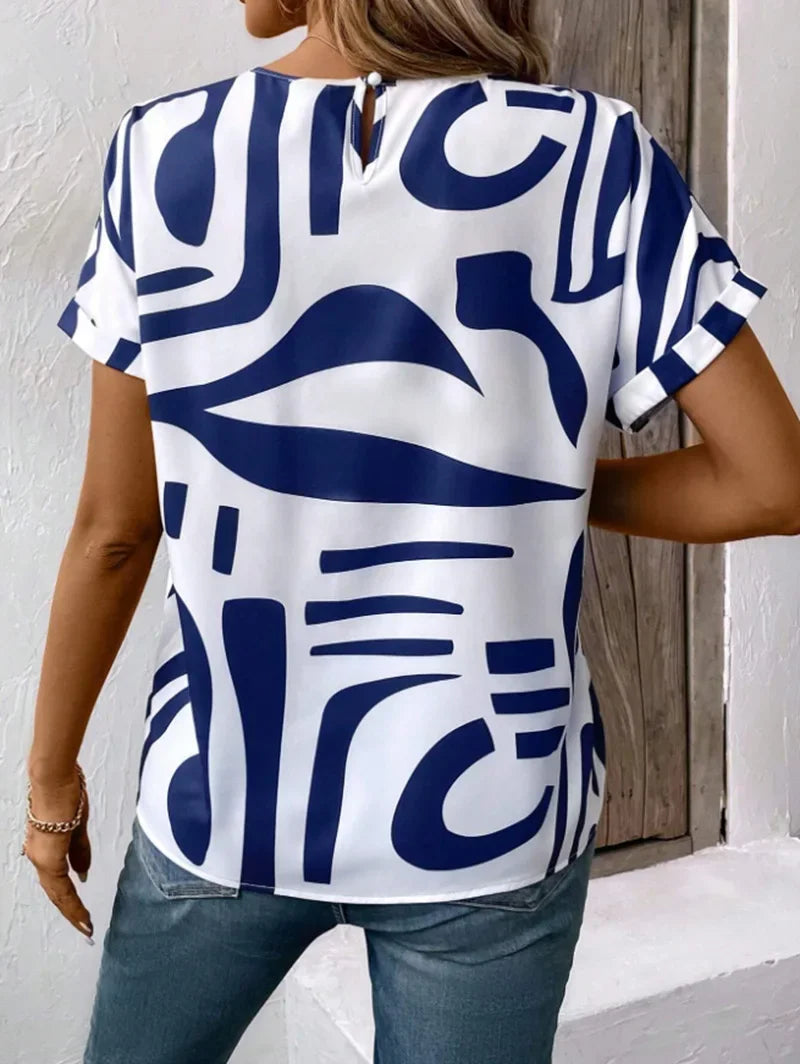 White short-sleeve blouse with bold blue geometric print and a relaxed, wide-cut silhouette