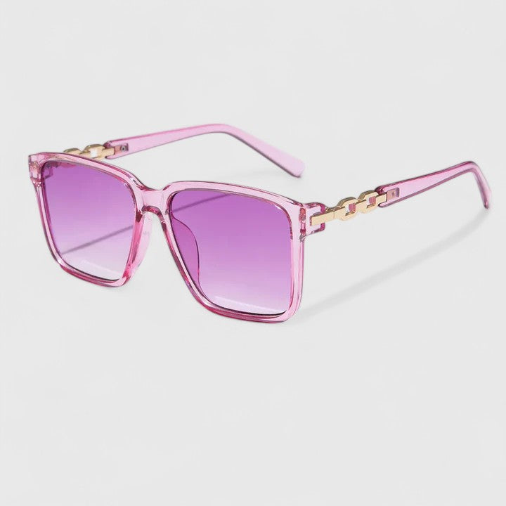 A woman by the pool wearing bold square sunglasses with chain-detail temples, confident in the sun.