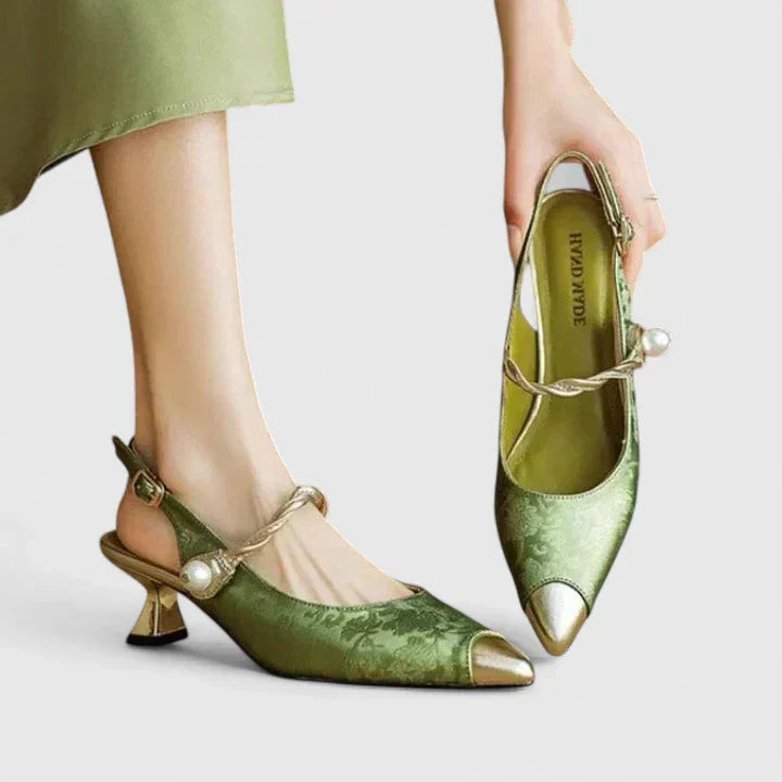 A woman standing elegantly in low cushioned kitten heels with a wide, supportive fit.