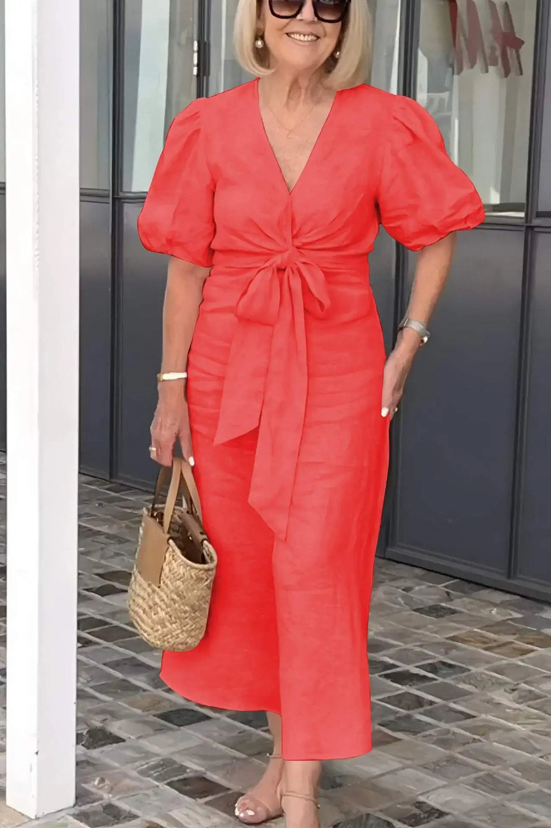 Woman wearing the Bridget bow-front midi dress with puff sleeves at a garden party.