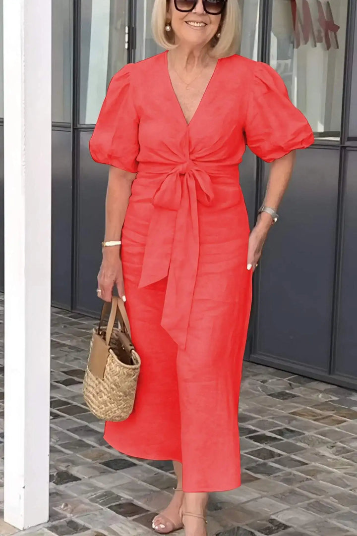 Woman wearing the Bridget bow-front midi dress with puff sleeves at a garden party.