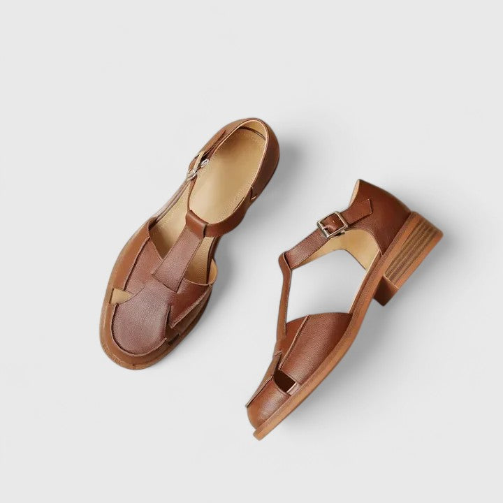 A woman wearing brown Mary Jane sandals with a T-strap and buckle, paired with a summer dress.