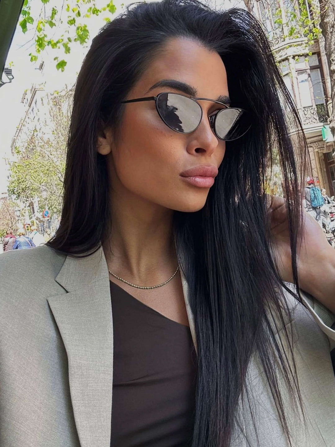 A woman wearing timeless slim black cat-eye sunglasses on an autumn day.