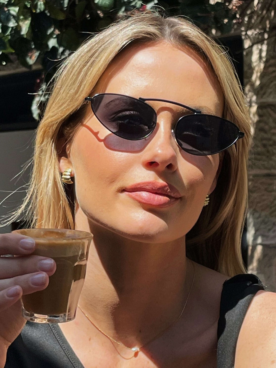 A woman wearing timeless slim black cat-eye sunglasses on an autumn day.