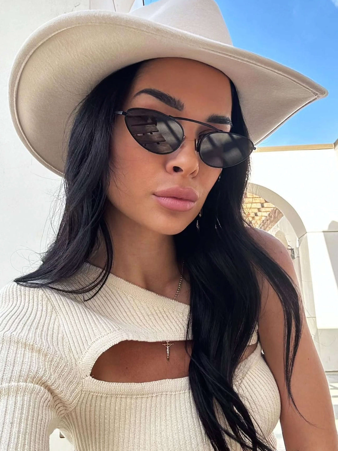 A woman wearing timeless gold-and-black cat-eye sunglasses on an autumn day.