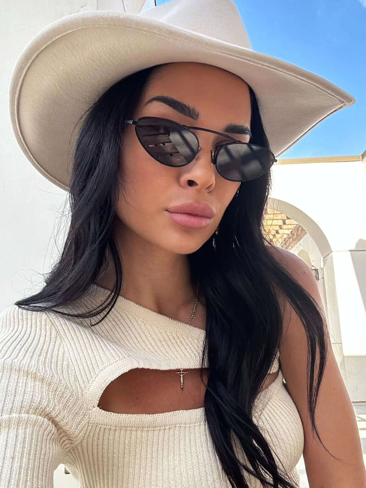 A woman wearing timeless slim black cat-eye sunglasses on an autumn day.