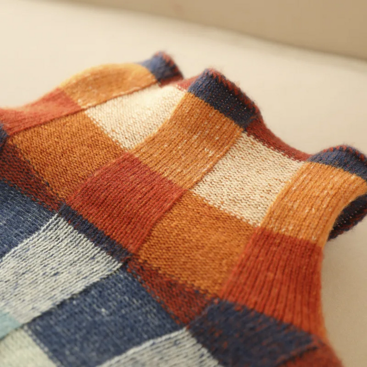 A woman wearing a colourful retro check jumper, relaxed and cosy on a cool autumn morning.