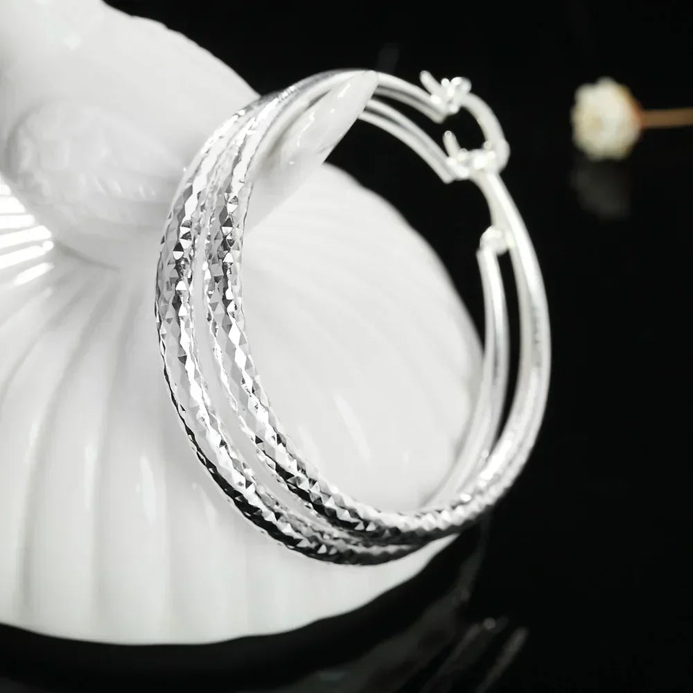 A pair of polished 925 sterling silver circular hoop earrings with a high-shine finish