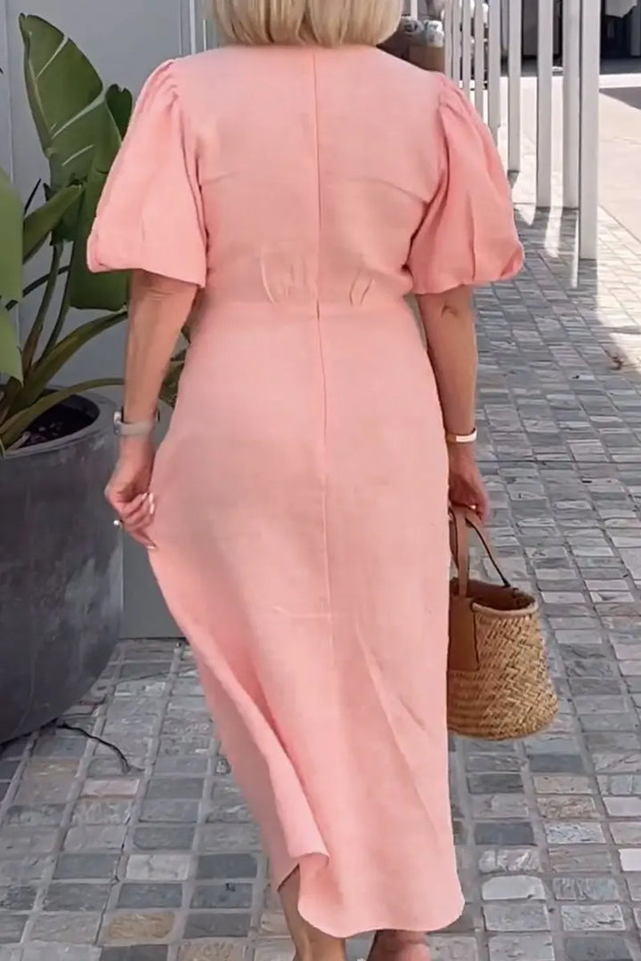 Woman wearing the Bridget bow-front midi dress with puff sleeves at a garden party.