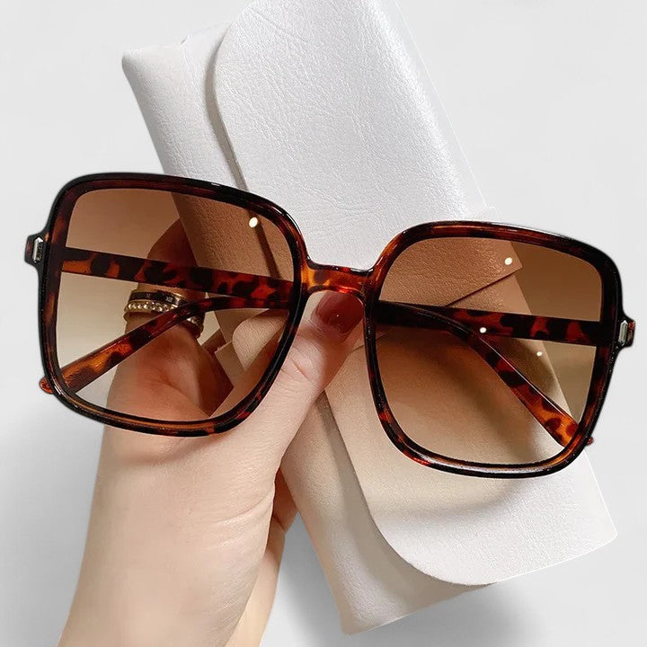 A woman wearing vintage-inspired oversized sunglasses in the sun, elegant and relaxed.