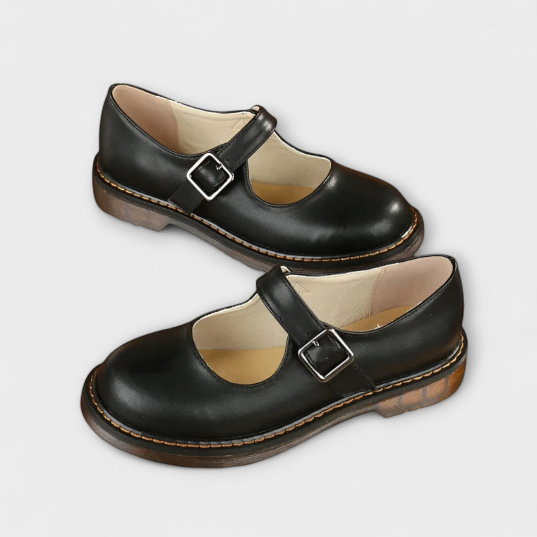A woman wearing classic black Mary Jane flats with a dress, looking smart and comfortable.