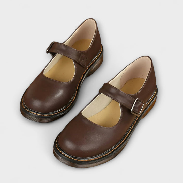 A woman wearing classic black Mary Jane flats with a dress, looking smart and comfortable.