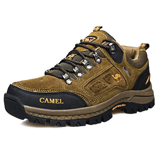 Men's khaki outdoor hiking boot with a rugged sole and lace-up front on a trail setting