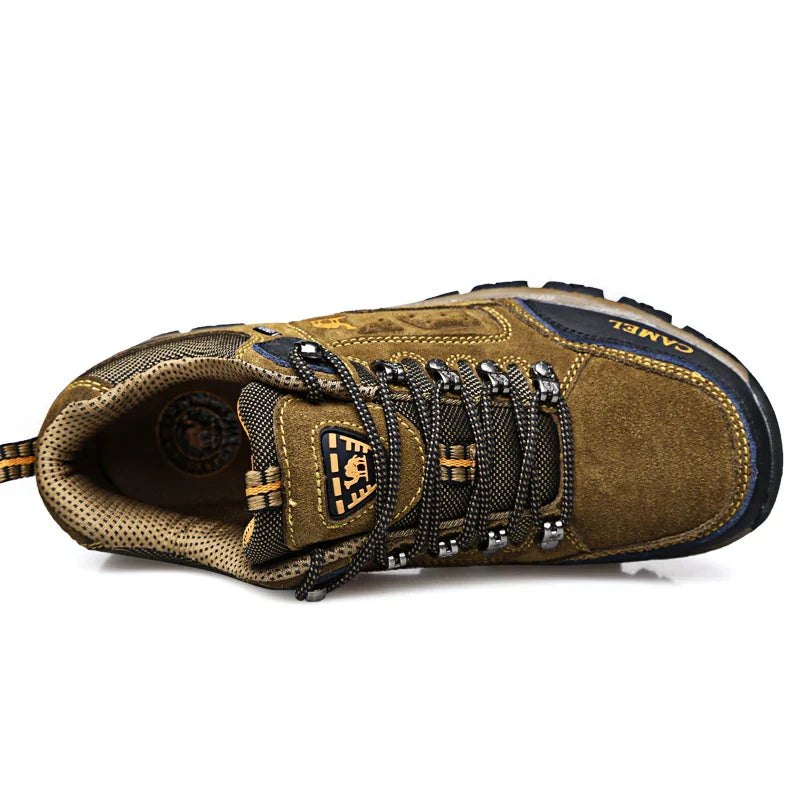Men's khaki outdoor hiking boot with a rugged sole and lace-up front on a trail setting