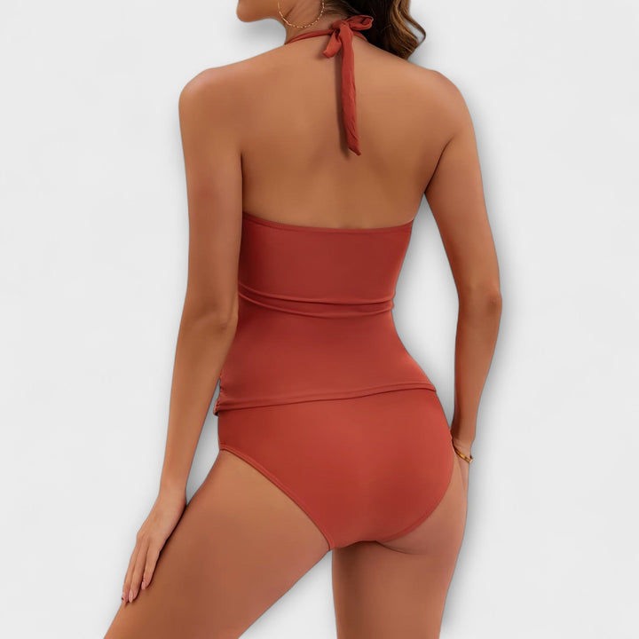 A woman by the water in a lively printed two-piece swimsuit, relaxed and confident in the sun.