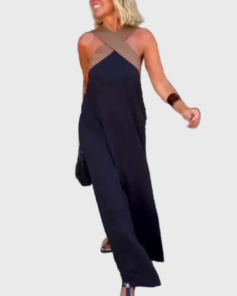 Woman wearing the Mary halterneck maxi dress in navy with a contrast crossover neckline, walking outdoors.
