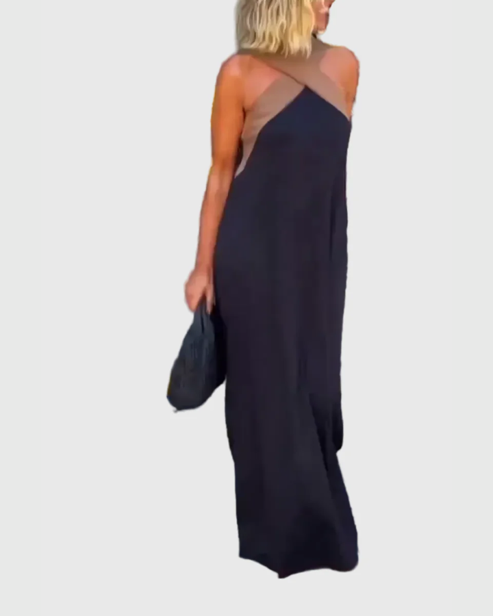 Woman wearing the Mary halterneck maxi dress in navy with a contrast crossover neckline, walking outdoors.