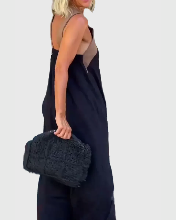 Woman wearing the Mary halterneck maxi dress in navy with a contrast crossover neckline, walking outdoors.