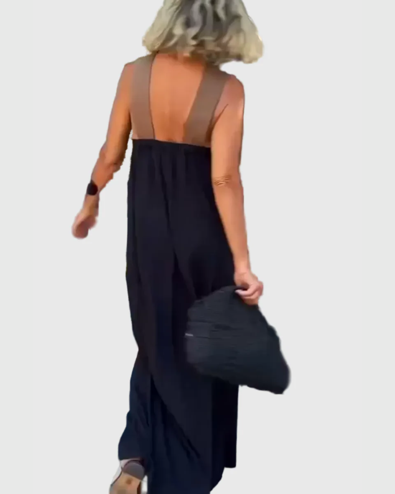 Woman wearing the Mary halterneck maxi dress in navy with a contrast crossover neckline, walking outdoors.