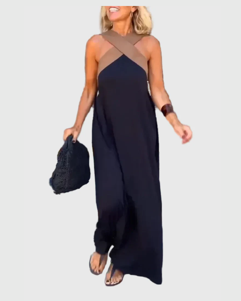 Woman wearing the Mary halterneck maxi dress in navy with a contrast crossover neckline, walking outdoors.