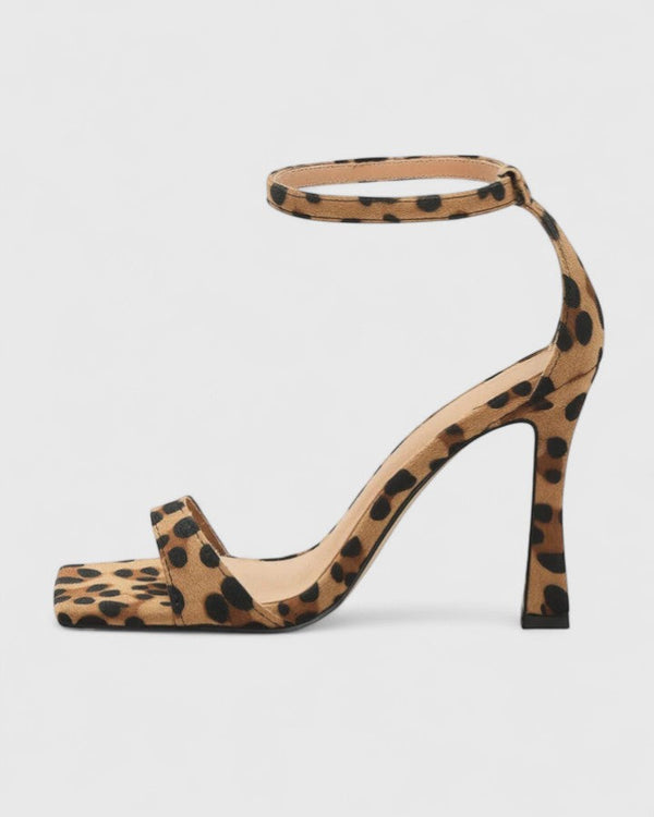 A woman wearing leopard print strappy heels with a square open toe and a thin ankle strap on a night out.