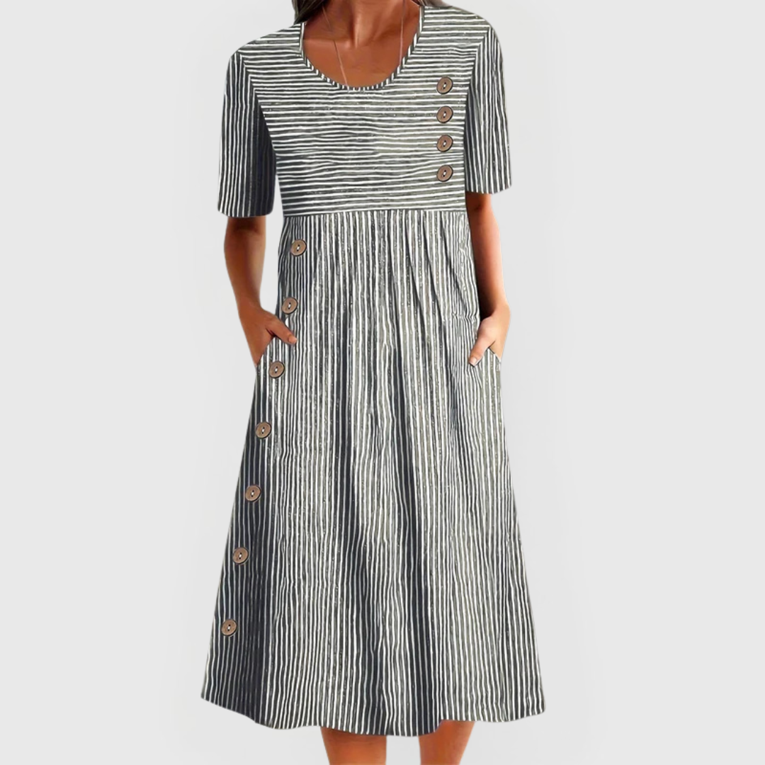 A woman wearing the Margaret striped midi dress with button details, standing outdoors on a bright day.