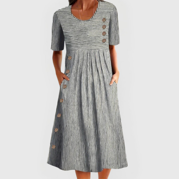A woman wearing the Margaret striped midi dress with button details, standing outdoors on a bright day.