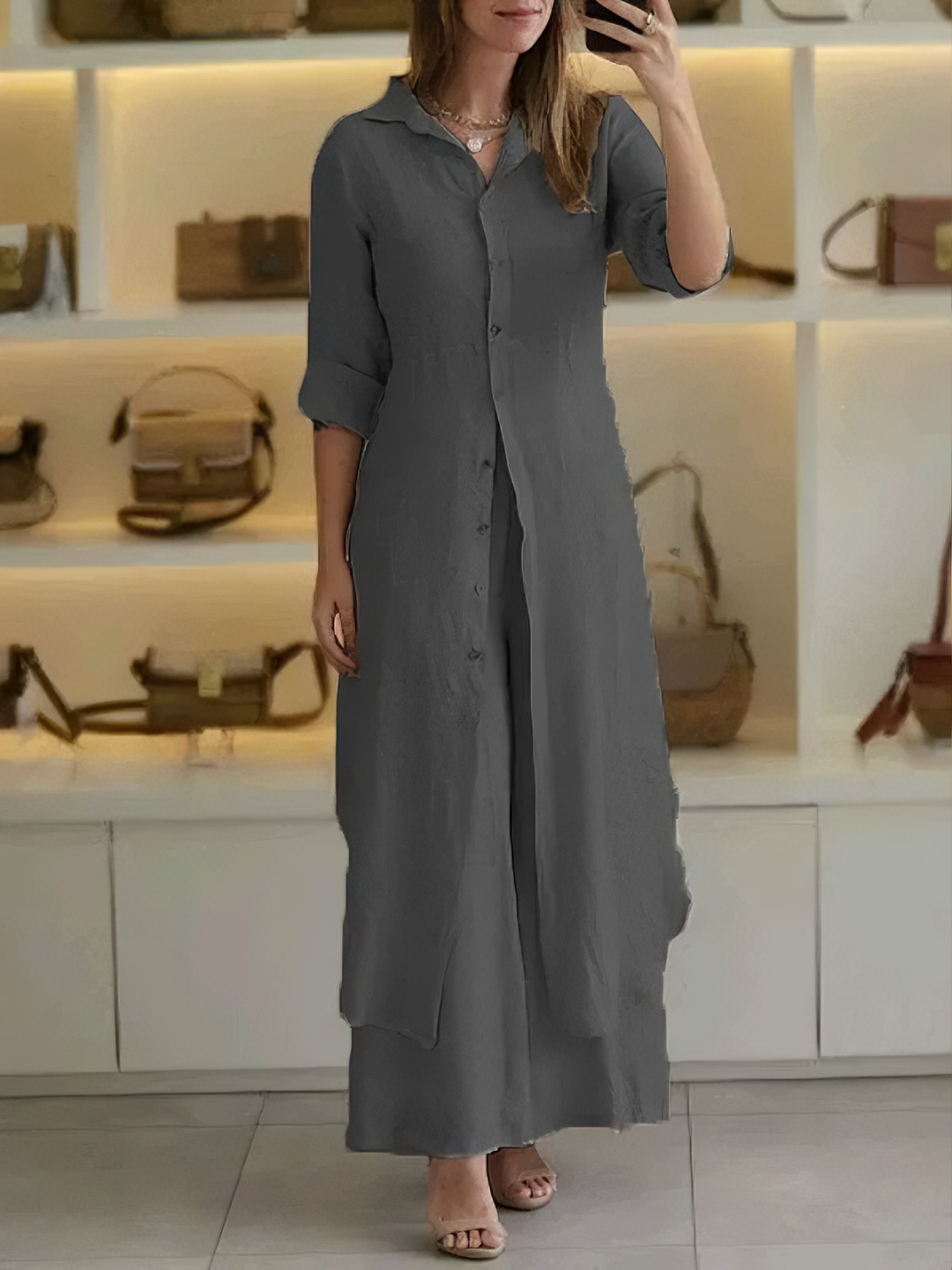 A woman wearing an elegant dress layered with flowing wide-leg trousers.