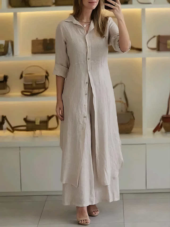 A woman wearing an elegant dress layered with flowing wide-leg trousers.
