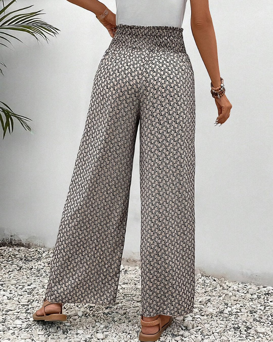 A woman wearing wide, flowing trousers in a beige-and-black geometric print with an elastic drawstring waist.