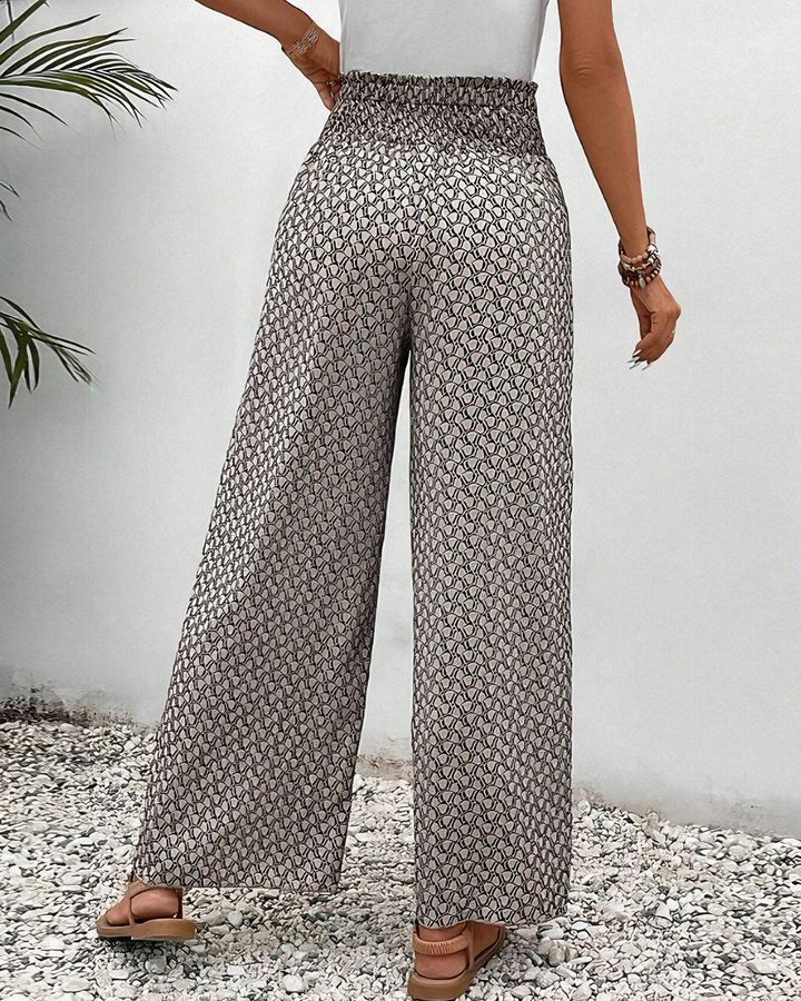A woman wearing wide, flowing trousers in a beige-and-black geometric print with an elastic drawstring waist.