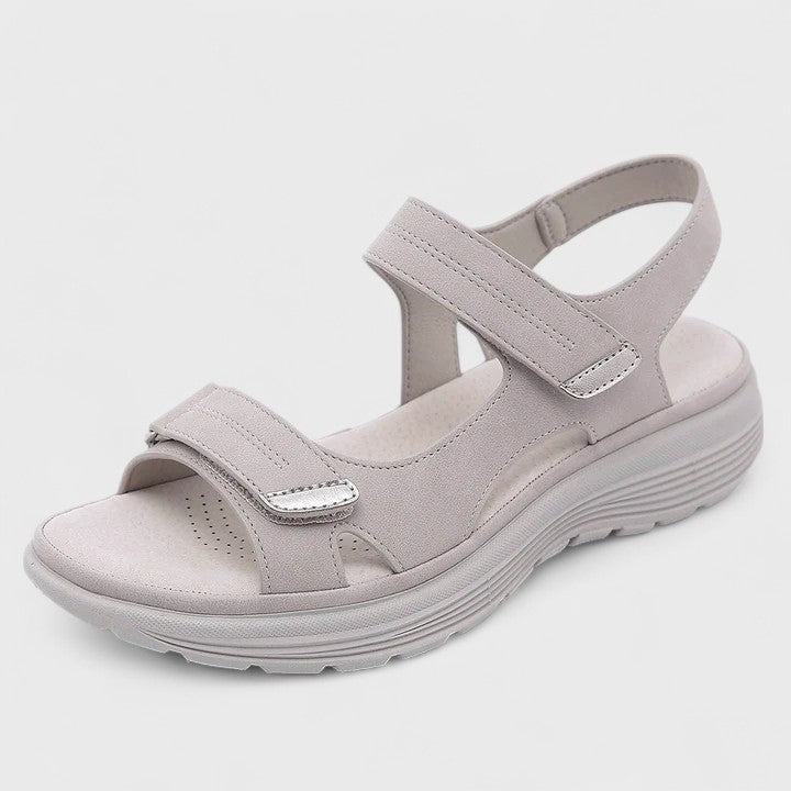 A woman walking gracefully in blue support sandals with a broad, cushioned footbed.