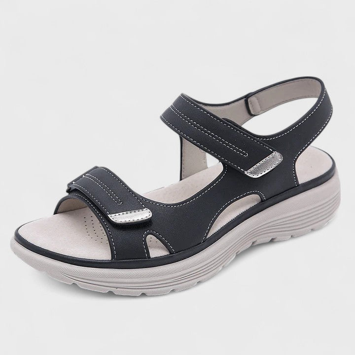 A woman walking gracefully in blue support sandals with a broad, cushioned footbed.