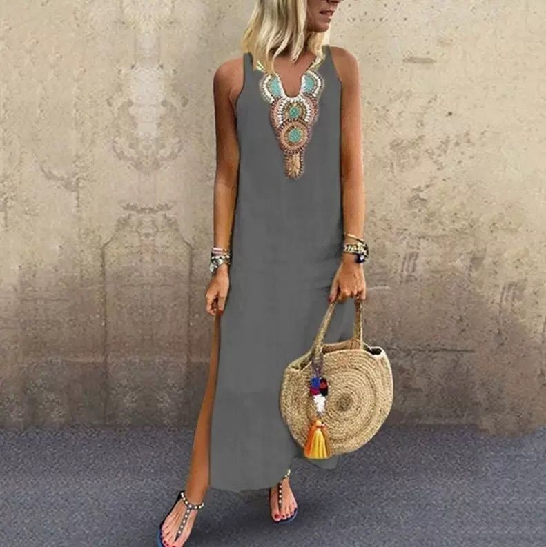 Woman in a sleeveless midi dress with embroidered neckline strolling in the summer sun.