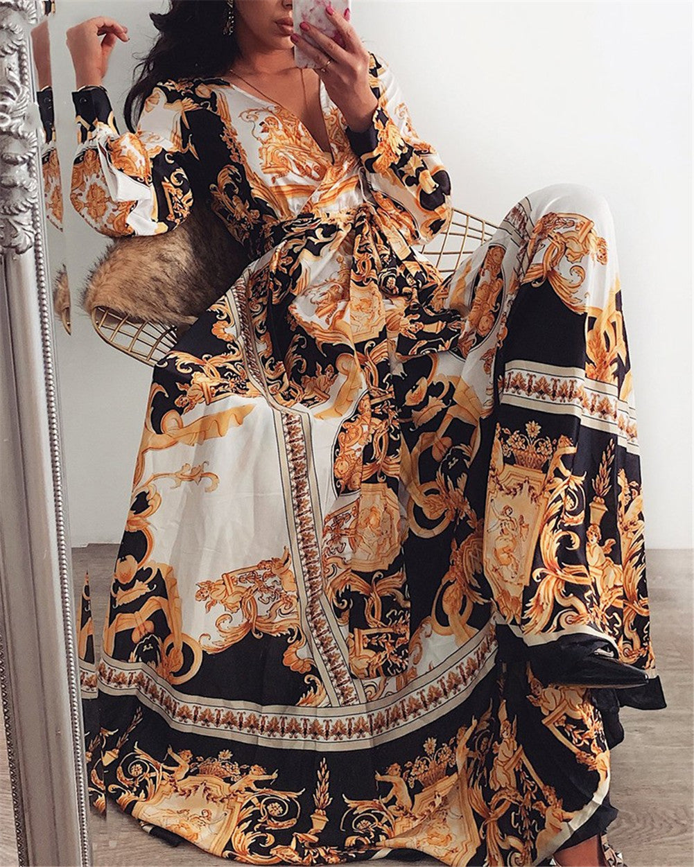 Woman at golden hour wearing the Tessa vintage print maxi dress with a waist belt and long statement sleeves.