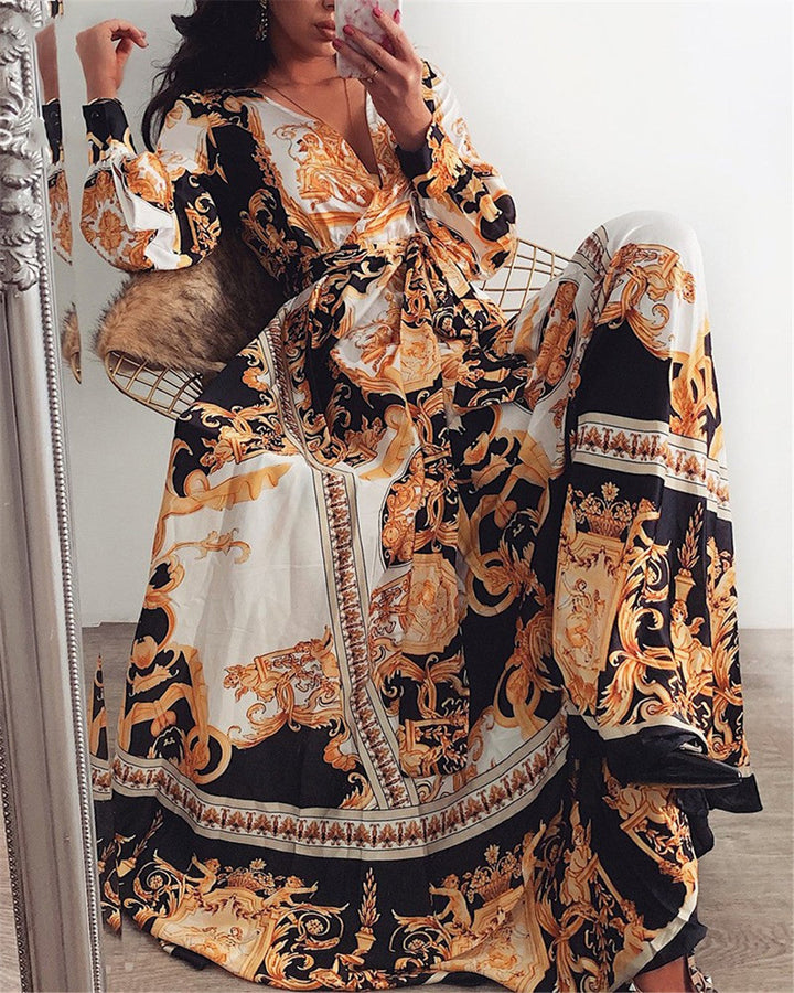 Woman at golden hour wearing the Tessa vintage print maxi dress with a waist belt and long statement sleeves.