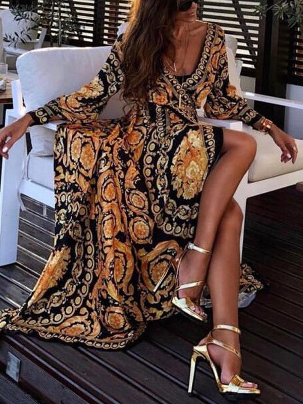 Woman at golden hour wearing the Tessa vintage print maxi dress with a waist belt and long statement sleeves.