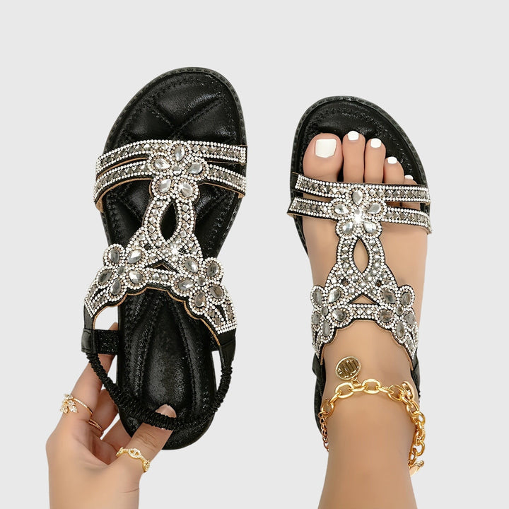 A woman wearing elegant gold open-front sandals with supportive straps and a cushioned sole.