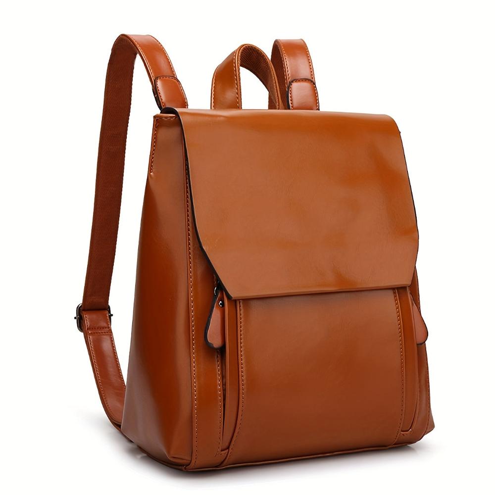 A woman wearing a padded vintage-style backpack over both shoulders while walking through the city.