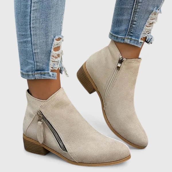 Woman wearing light blue vintage-style ankle boots, walking along a leafy street.
