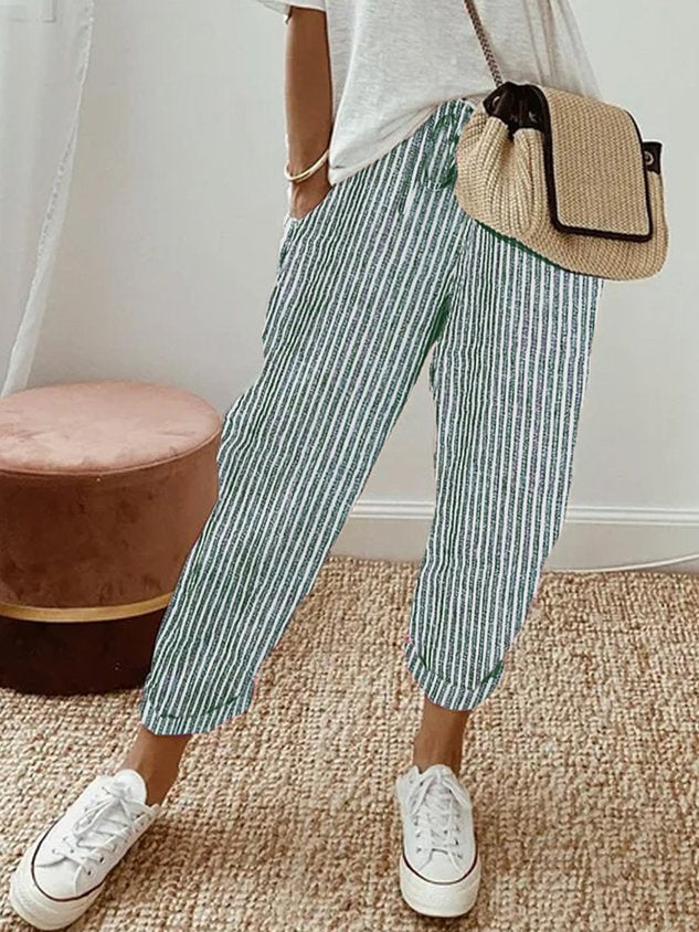 A woman wearing flowing elegant trousers with a soft elastic waist and deep pockets.