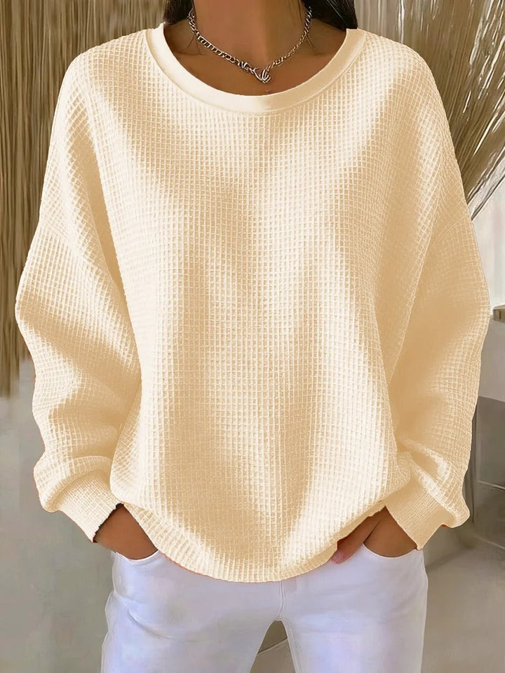 A woman wearing a relaxed-fit waffle-stitch jumper in soft pink with a textured surface