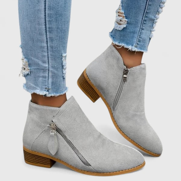 Woman wearing light blue vintage-style ankle boots, walking along a leafy street.